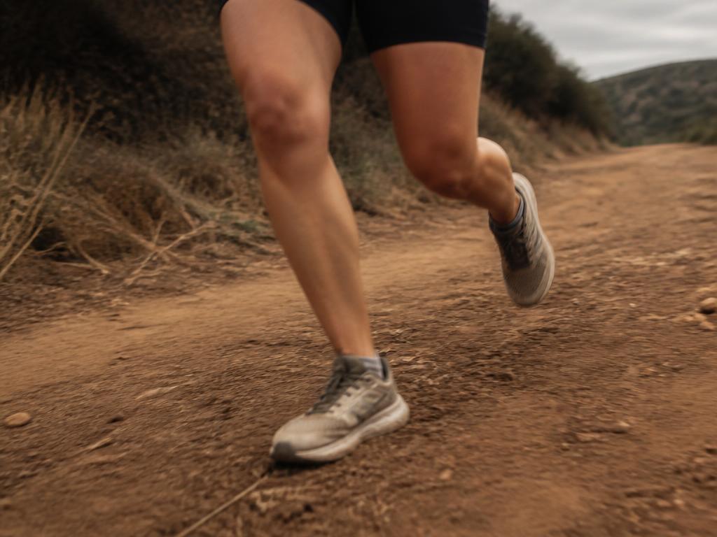 A runner's legs mid-stride on a dirt trail
